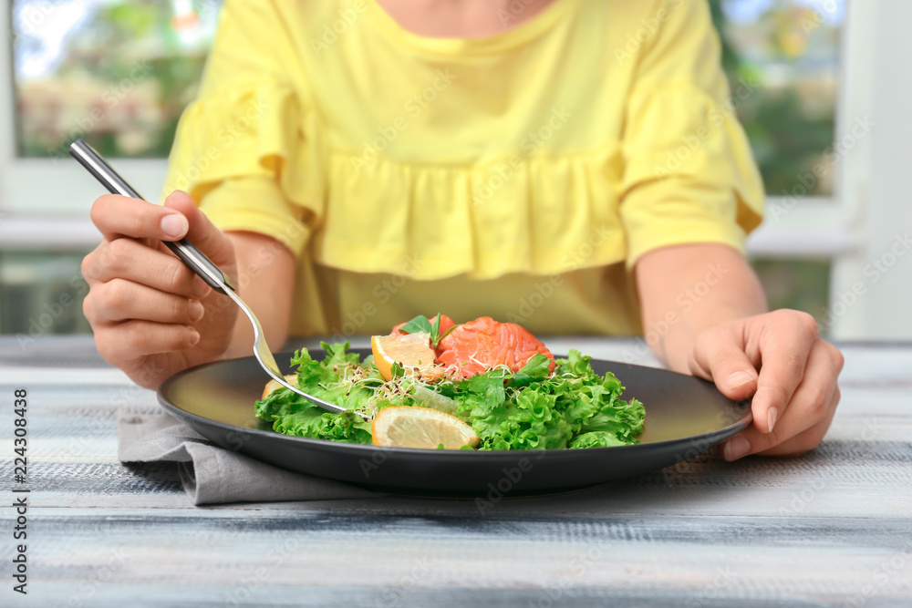 Woman eating fresh salad with salmon at table Woman eating fresh salad with salmon at table