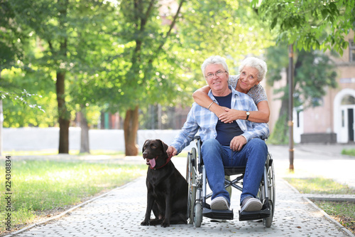 Senior man in wheelchair with his wife and dog outdoors