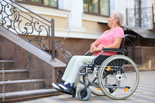 Senior woman in wheelchair near stairs outdoors