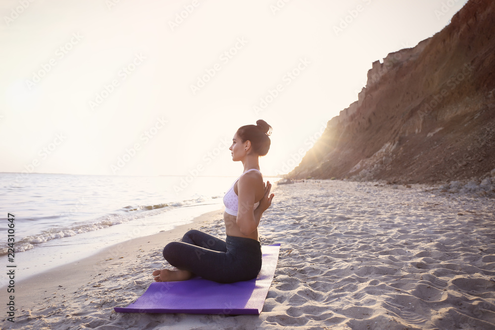 Fototapeta premium Woman practicing yoga on sea shore