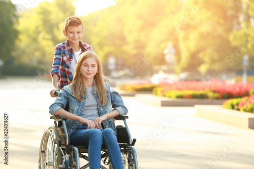 Teenage girl in wheelchair and her brother outdoors