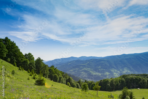 Mountain view. Blue sky with clouds. Green grass fields on sunny day