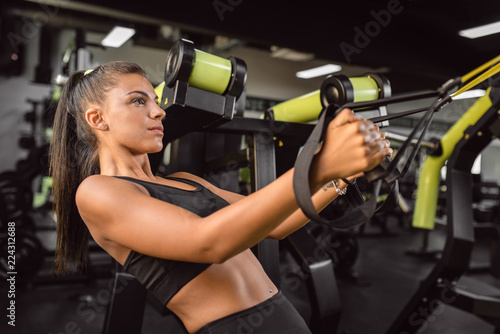 Girl in a jim doing exersises with trx