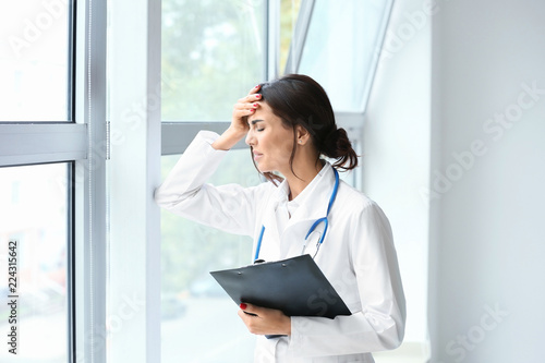 Tired female doctor near wi...