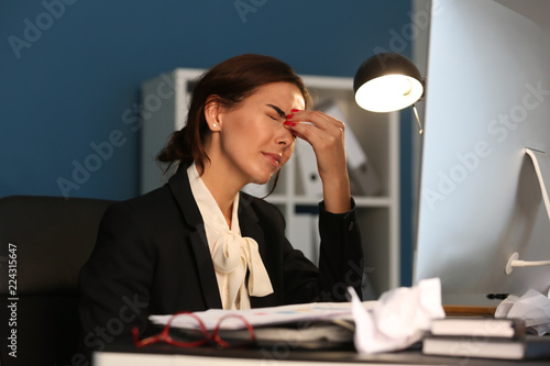 Tired woman working late in...