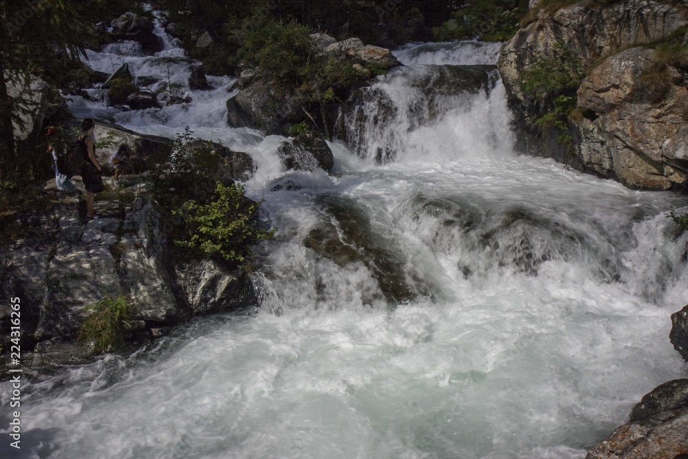 A mountain stream flows with its impetuous waters between the rocks A mountain stream flows with its impetuous waters between the rocks