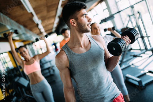 Muscular bodybuilder workout in gym doing biceps exercises