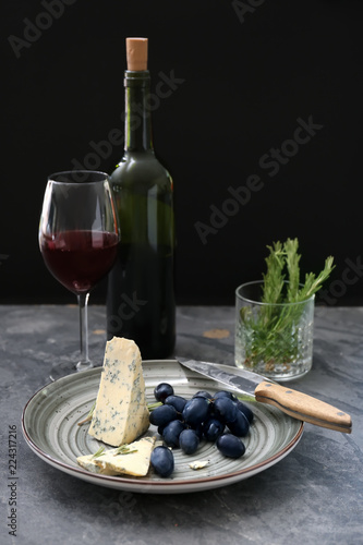 Ripe juicy grapes with cheese and red wine on grey table