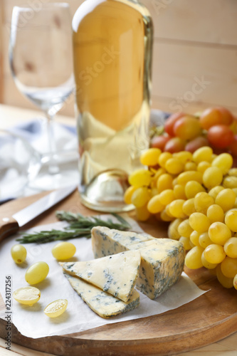 Ripe juicy grapes with cheese and white wine on wooden board