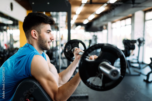 Athlete muscular bodybuilder in gym training biceps