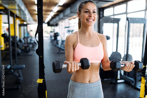 Young woman doing exercise with dumbbell in gym
