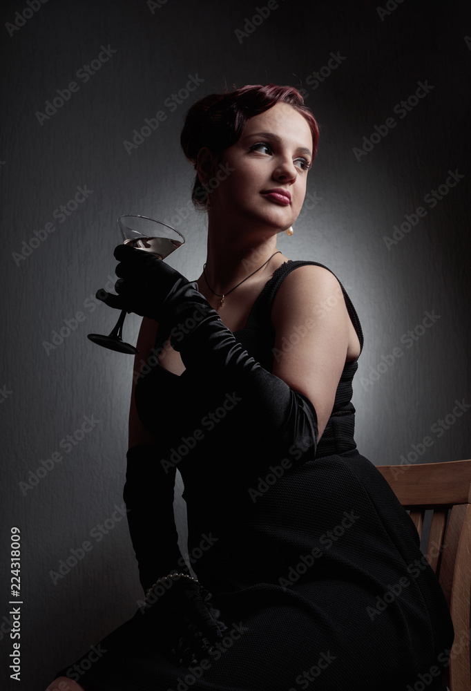 Beautiful woman in black dress  with glass of martini .
