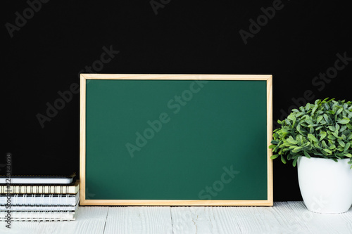 Back to school and education concept  green chalkboard with pile of notebook paper  stationery or school supplies.