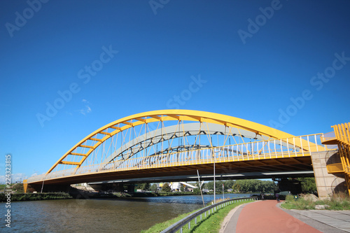 Bright yellow bridge named Hogeweidebrug over the Amsterdam-Rhine canal in Utrecht for traffic and Vleutenspoorbrug which is a trainbridge.