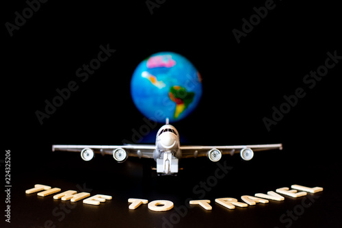 Travel concept. Mock up image of airplane model and text" Time to travel " with global world dark blurred background. Blank space for your text and content design.