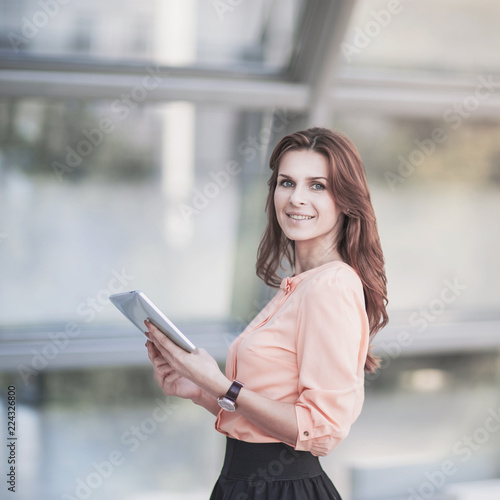 successful business woman with digital tablet standing in the lobby of a modern office