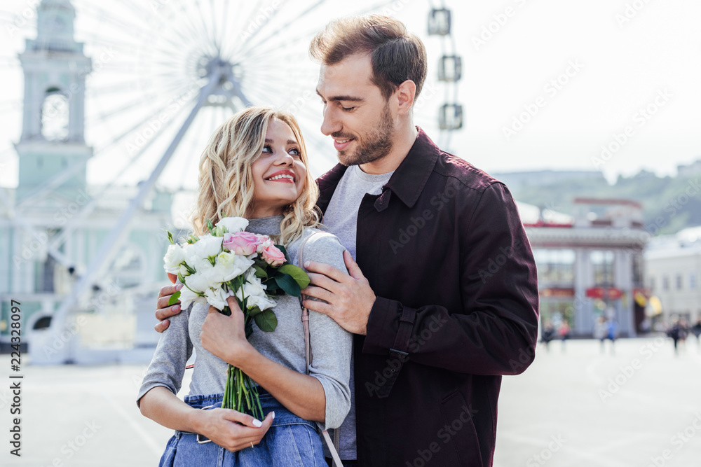 boyfriend hugging girlfriend with bouquet in city boyfriend hugging girlfriend with bouquet in city