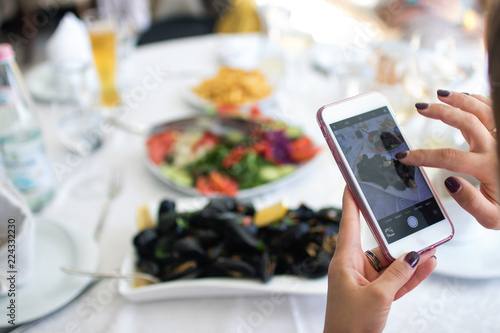 Women's hands take pictures of boiled mussels served on the table. Albania. Adriatic coast. National food. photo