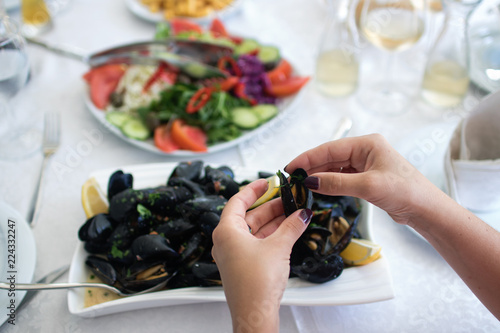 Women's hands open of boiled mussels served on the table. Albania. Adriatic coast. National food. photo