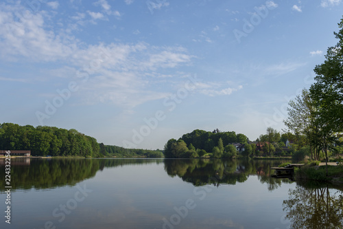 Fototapeta Naklejka Na Ścianę i Meble -  View over lake Herrenteich with calm water and forest reflecting in the water