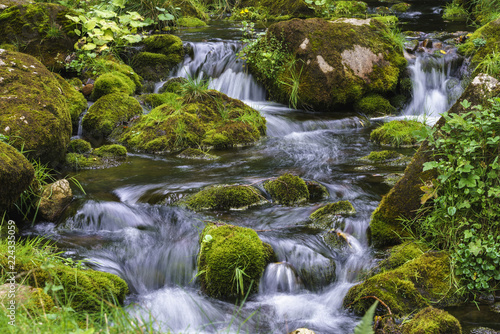 Mountain stream cascading over moss covered rocks wot long exposure motion blur