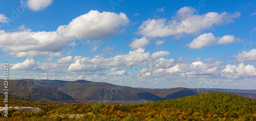 panoramic autumn landscape with forest hills and blue sky with clouds