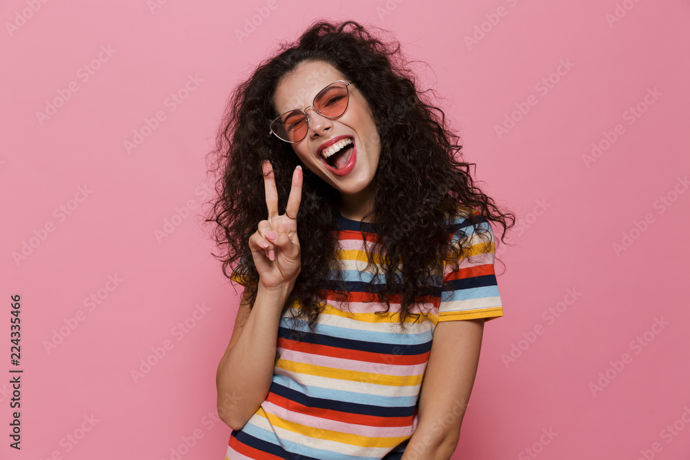 Cute young woman posing isolated over pink background make peace gesture. Cute young woman posing isolated over pink background make peace gesture.