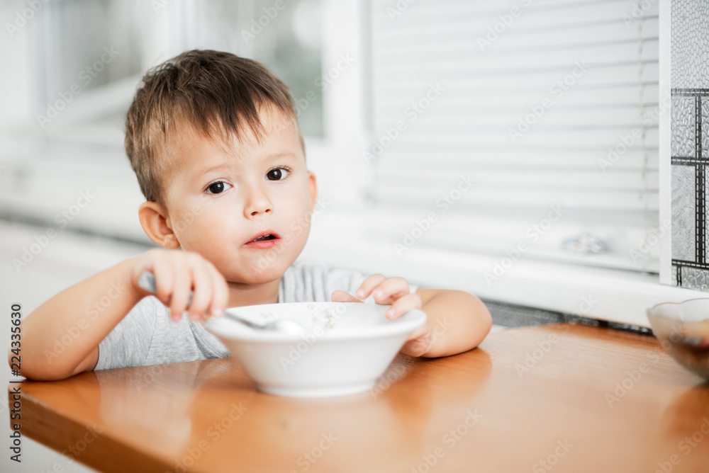 charming child in the kitchen eating oatmeal charming child in the kitchen eating oatmeal