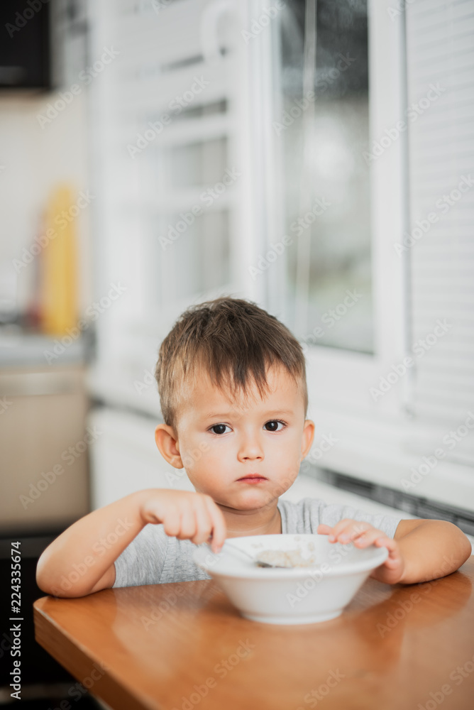 charming child in the kitchen eating oatmeal charming child in the kitchen eating oatmeal