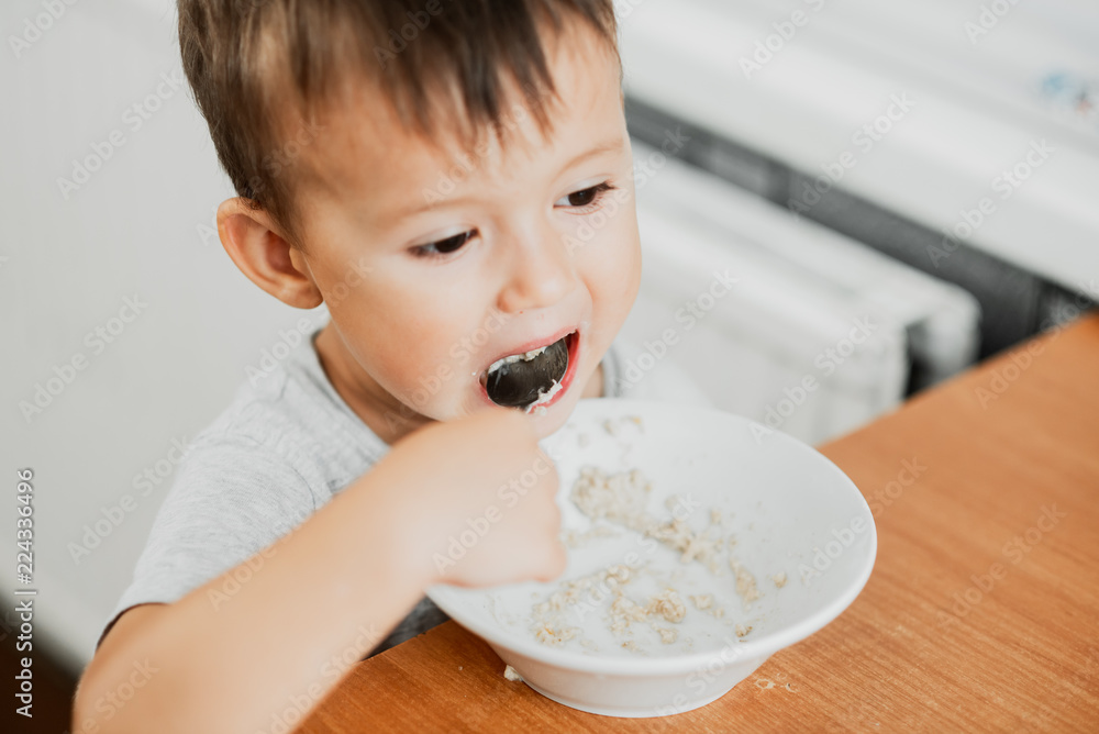 charming child in the kitchen eating oatmeal charming child in the kitchen eating oatmeal