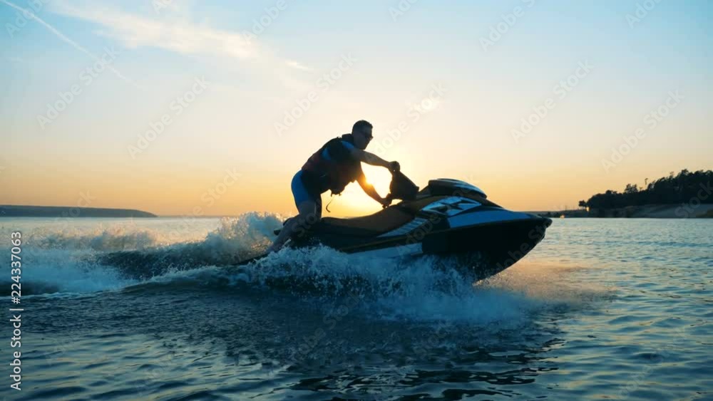 Person drives on a waverunner on a sunset background, side view. Person drives on a waverunner on a sunset background, side view.
