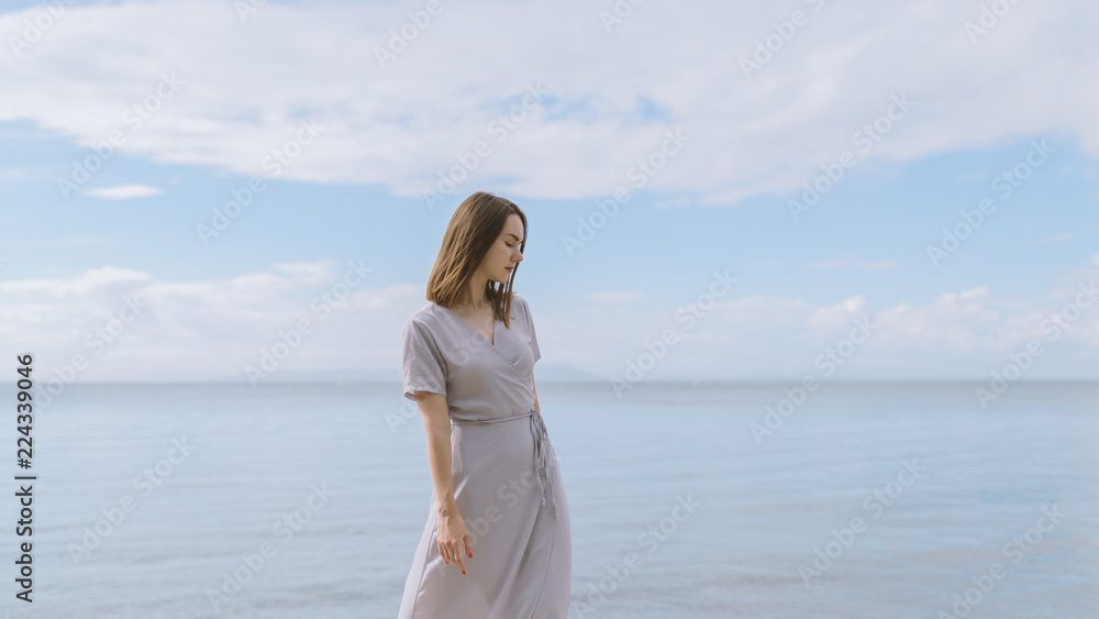 Woman in dress enjoys a walking near the sea shore.