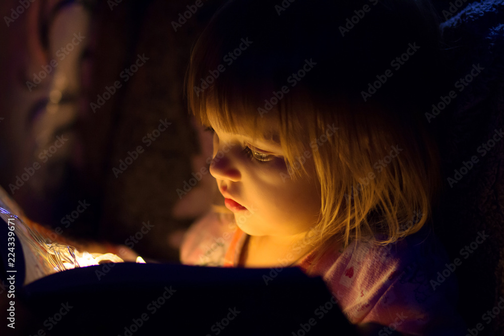The girl reads the book, from the book light on the person, a close up shines The girl reads the book, from the book light on the person, a close up shines