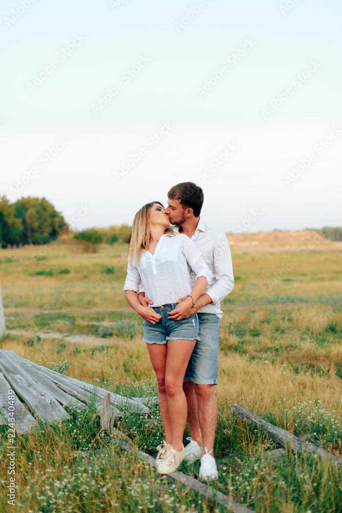 Young beautiful enamored couple walking outdoors in summer at sunset