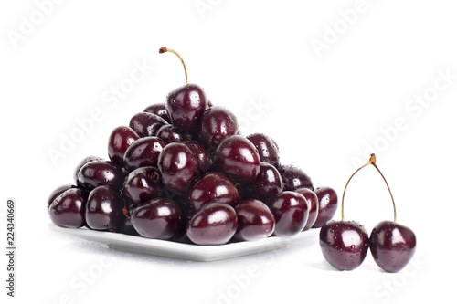 Cherry berries in water drops on a white plate on a white background isolated