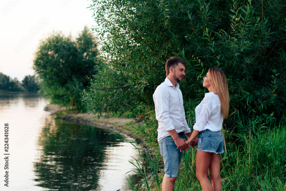 Young beautiful enamored couple walking outdoors in summer at sunset Young beautiful enamored couple walking outdoors in summer at sunset