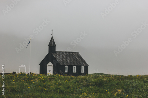 dramatic shot of Budir church on green field at Snaefellsnes, Iceland