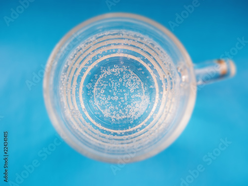 Glass cup with bubbles of air on blue background. Selective focus wtih shallow depth of field. Top view,