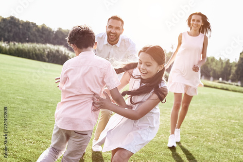 Bonding. Family of four running on grassy field playing playing  © Friends Stock