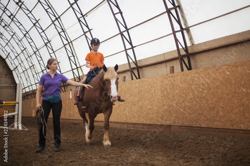 Boy in helmet learning Horseback Riding with instructor © olsima