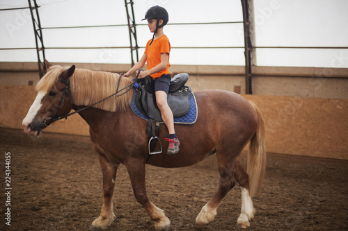 Boy in helmet learning Horseback Riding