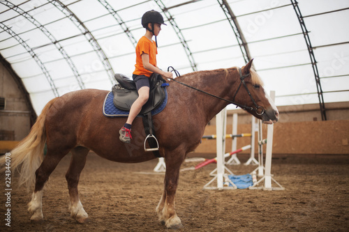 Boy in helmet learning Horseback Riding