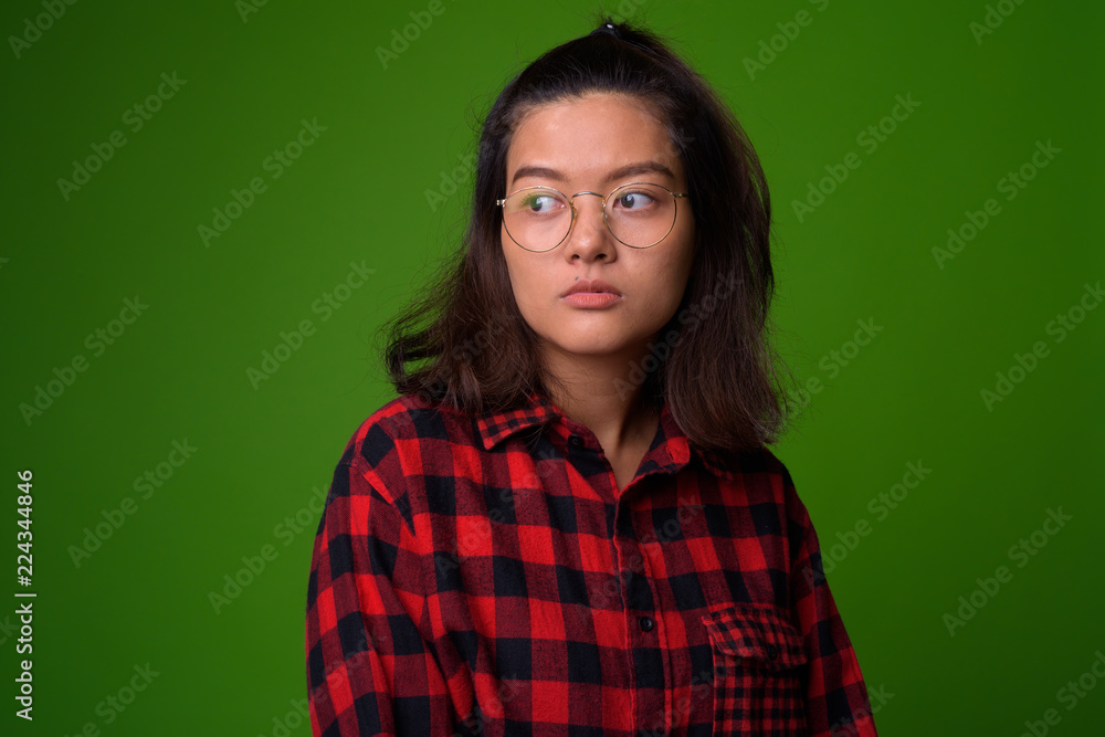 Fototapeta premium Young beautiful Asian hipster woman wearing eyeglasses and red checkered shirt