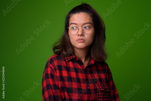 Young beautiful Asian hipster woman wearing eyeglasses and red checkered shirt © Ranta Images
