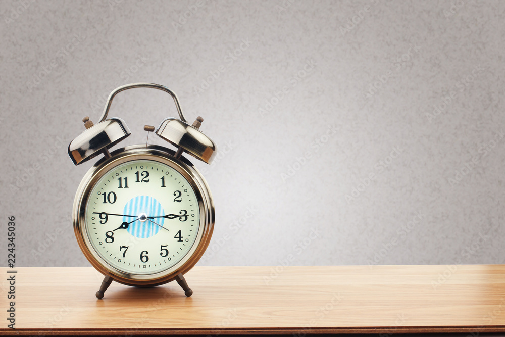 Retro alarm clock on wooden table with purple wall background Retro alarm clock on wooden table with purple wall background