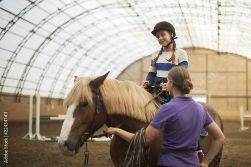 Teen girl in helmet learning Horseback Riding