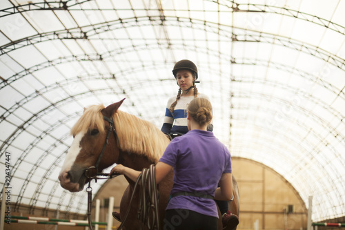 Teen girl in helmet learning Horseback Riding