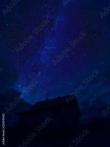 Star tracks upon village house. Starry night sky in cloudy weather. Kenozersky National Park, Arkhangelsk region, Russia.