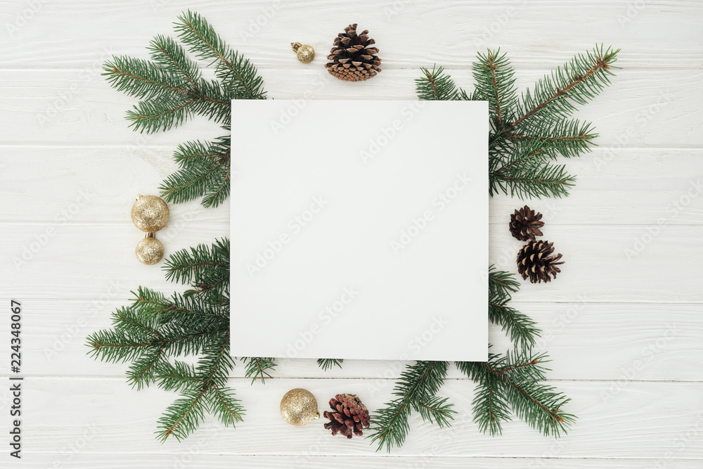 top view of blank white card with evergreen twigs, pine cones and golden christmas balls top view of blank white card with evergreen twigs, pine cones and golden christmas balls
