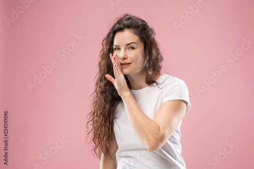 Secret, gossip concept. Young woman whispering a secret behind her hand. Business woman isolated on trendy pink studio background. Young emotional woman. Human emotions, facial expression concept.